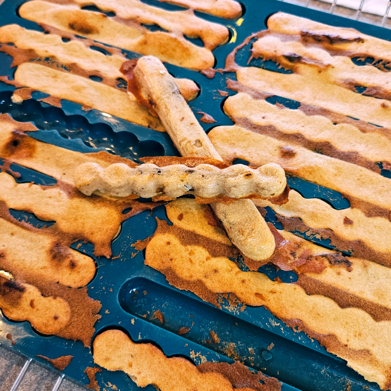 Leckerchen-Rezepte für Hunde Eine blaue Backmatte von collory für Kaustangen mit Leckerchen dadrin. Eine Kaustange liegt oben drauf.